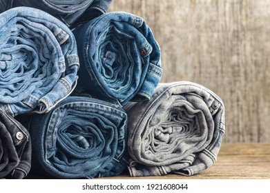 Stack Of Various Denim Jeans, Trousers On Wooden Rustic Background, Fashion Design 