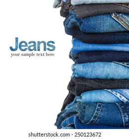 stack of various shades of blue jeans on white background