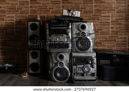 Stack of vintage audio stereo systems and old speakers against a brown brick wall background