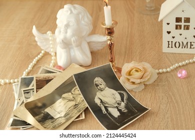 Stack Of Vintage Photos On Table, Romantic Still Life In Love Style, Cupid With Wings, Candles Burning, Concept Of Family Tree, Genealogy, Childhood Memories