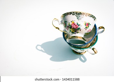 Stack Of Vintage Porcelain Tea Cups With Floral And Golden Decorations On White Background. Concept Of Afternoon Tea Party And Fine Bone China