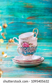 Stack of vintage tea cups on turquoise background