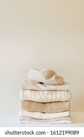 A stack of warm beige knit sweaters. The concept of capsule wardrobe, comfort. Close-up with copy space for text.