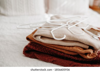 Stack of warm sweaters being put on hangers and prepared for winter and fall season.