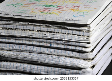 A stack of well-used notebooks with worn edges and colorful scribbles on the top cover, showcasing creativity and everyday use. Ideal for education or writing-related themes.