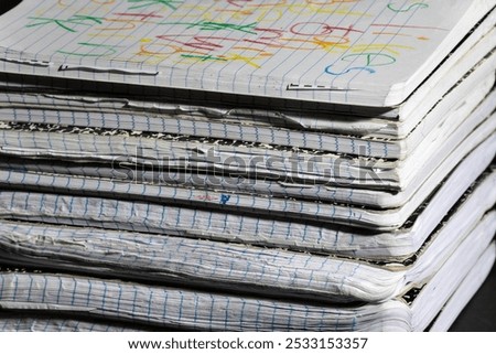 A stack of well-used notebooks with worn edges and colorful scribbles on the top cover, showcasing creativity and everyday use. Ideal for education or writing-related themes.