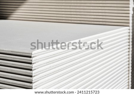 The stack of WHITE drywall Standard Gypsum board panel. Plasterboard. Panel Type A designed for indoor walls, partitions and ceilings, construction site