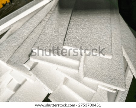 A stack of white expanded polystyrene (EPS) foam sheets or styrofoam boards showing grainy texture, commonly used for thermal insulation, protective packaging, or craft projects.