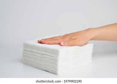 Stack white napkins in hand on white background isolation. Paper napkins with female hand. Stack of clean paper napkins.