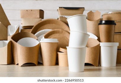 A stack of white paper cups on the background of eco-friendly disposable tableware. Zero waste concept, selective focus