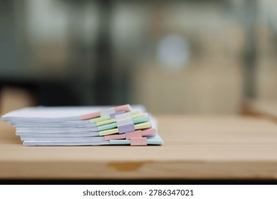 Stack of white papers with various colorful binder clips separating sections, symbolizing organized paperwork, financial records, administrative tasks, and efficient office management