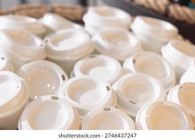 Stack of white plastic coffee cups with white lids in basket reusable cups