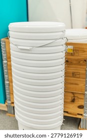 Stack of white plastic paint buckets in hardware store renovation supplies section.