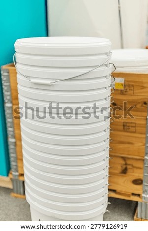 Stack of white plastic paint buckets in hardware store renovation supplies section.