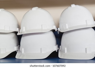 Stack of white plastic safety helmets on table