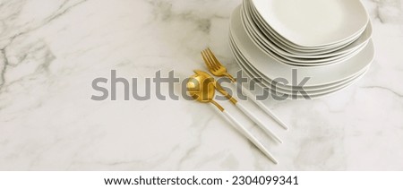 Stack of white plates and cutlery on white marble table top view with copy space banner.Modern kitchen tableware.Space for text or menu .Business food brand template.