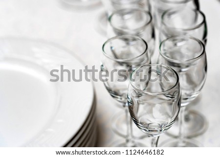 Stack of white plates and empty wine glasses