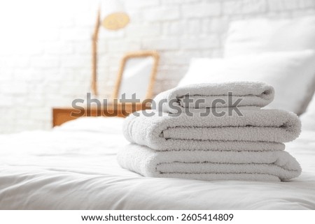 Stack of white soft towels on white bed at home, closeup
