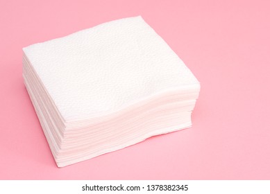 Stack of white square paper napkins on pink background