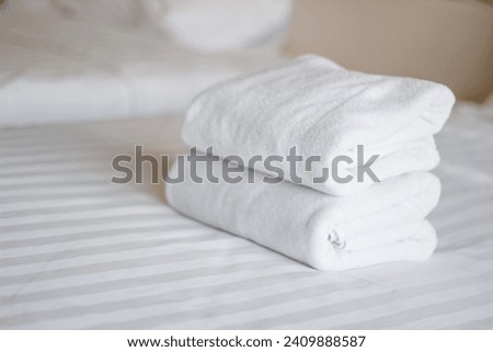Stack of white towels on bed in hotel