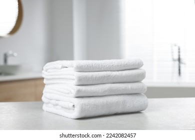 Pila de toallas blancas sobre la mesa en el cuarto de baño