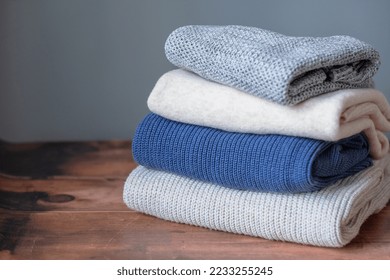 A stack winter warm knitted sweaters wooden background  Change season   wardrobe  Sustainable   ecological fashion  High quality photo