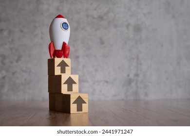 A stack of wooden blocks with arrows pointing upwards and rocket. Copy space for text.