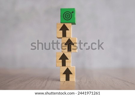 A stack of wooden blocks with arrows pointing upwards and target board. Mission, focus, ladder of success concept.