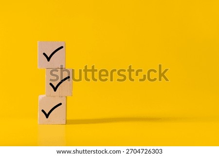 stack wooden blocks with checkmark symbol isolated on yellow background