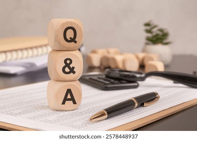 a stack of wooden blocks displaying Q and A on financial documents, symbolizing questions and answers in business. pen, calculator, office accessories in the background create a professional setting