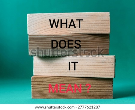 Stack of Wooden Blocks with "What Does It Mean?" Text Over Green Background