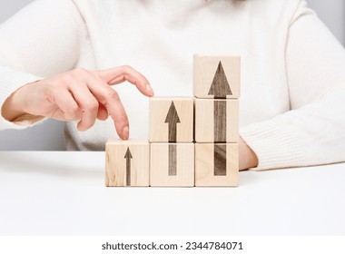 Stack of wooden cubes, the person's fingers go up the steps. Business growth concept, goal achievement, self-education, career success - Shutterstock ID 2344784071
