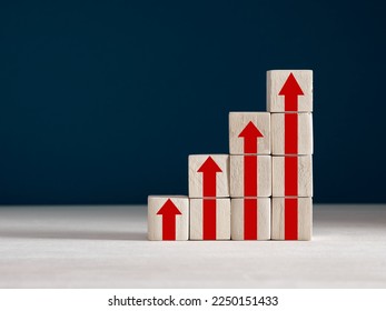 Stack of wooden cubes with red arrows going up. The process of successful business development, economy, increasing productivity, performance and profit concept.