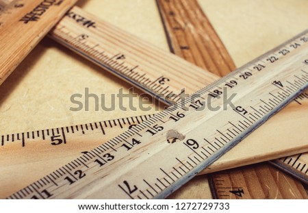 stack of wooden rulers on a tan table, rulers vary in color