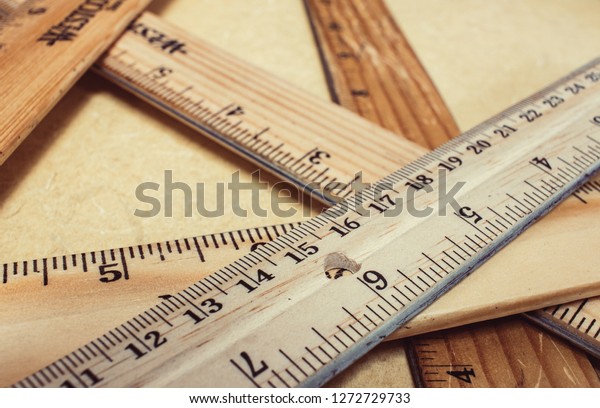 stack of wooden rulers on a tan table, rulers vary\
in color