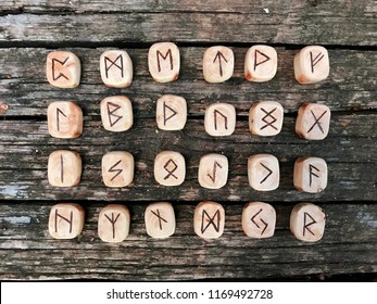 A stack of wooden runes at forest. Wooden runes lie on a old wood background. Runes are cut from wooden blocks. On each rune symbol for fortune telling is designated.