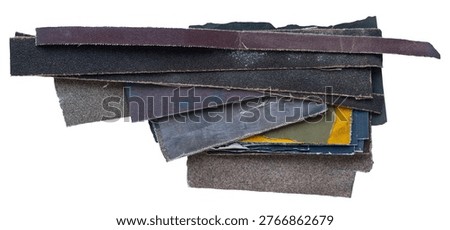 Stack of worn sandpaper sheets with rough textures, frayed edges and different colors isolated on white background