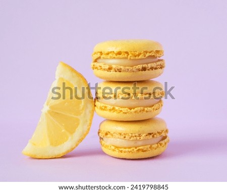 stack of yellow macarons, on a purple lilac backdrop, with lemon slice