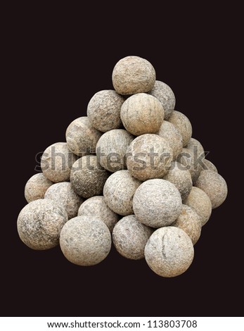 Stacked ancient Canon balls made of granite rock isolated on black
