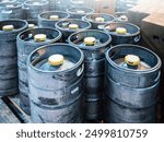 Stacked beer kegs at brewery yard, robust supply chain and storage of craft beer in industrial metal barrels with visible wear and tear