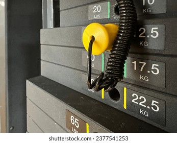 Stacked black metal or iron heavy plates for sports, exercise, weight machine with kilogram and pound numbers in the gym with blurred grey background.