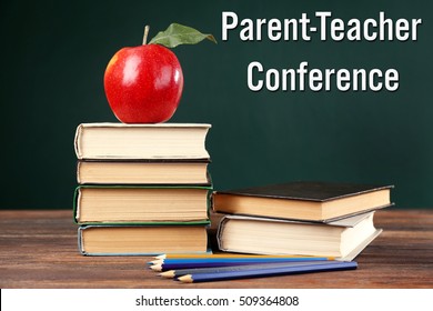 Stacked books with colorful pencils and apple on wooden table. Text PARENT-TEACHER CONFERENCE on chalkboard background. School concept.
