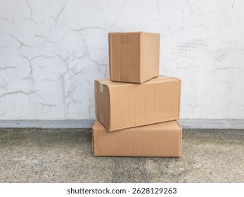 Stacked Cardboard Boxes Against a Cracked Wall, Ready for Shipping