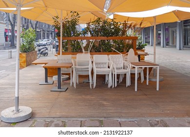 Stacked Chairs Under Parasols Restaurant Terrace