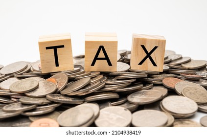 Stacked coins and wooden cube with TAX written on it. - Shutterstock ID 2104938419