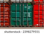Stacked colorful containers in red, green, grey and bordeaux in the harbour of Duisburg Ruhrort inland port Germany. Logistics shipping background with metal square fronts of big boxs with doors.