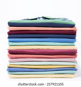 Stacked of colourful t-shirt on background