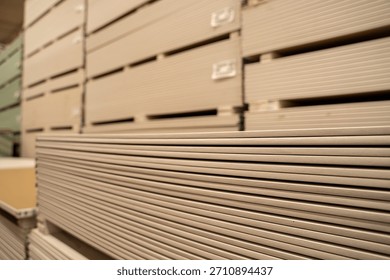 Stacked drywall sheets in hardware store aisle.