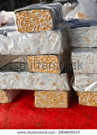 Stacked fermented tempeh blocks displayed for sale at a traditional market, representing nutritious soybean food and local culinary ingredients.