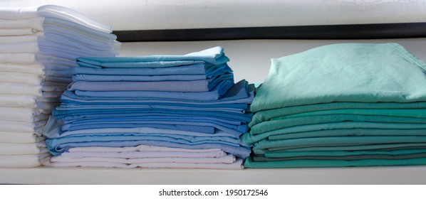 Stacked Green And Blue Surgical Clothing In An Industrial Laundry. Cleaning And Care Clothes Service For Clinics And Hospitals.